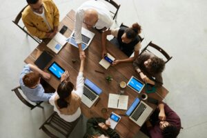 "Group of people sitting around an office table in a collaborative meeting discussing about employability skills."